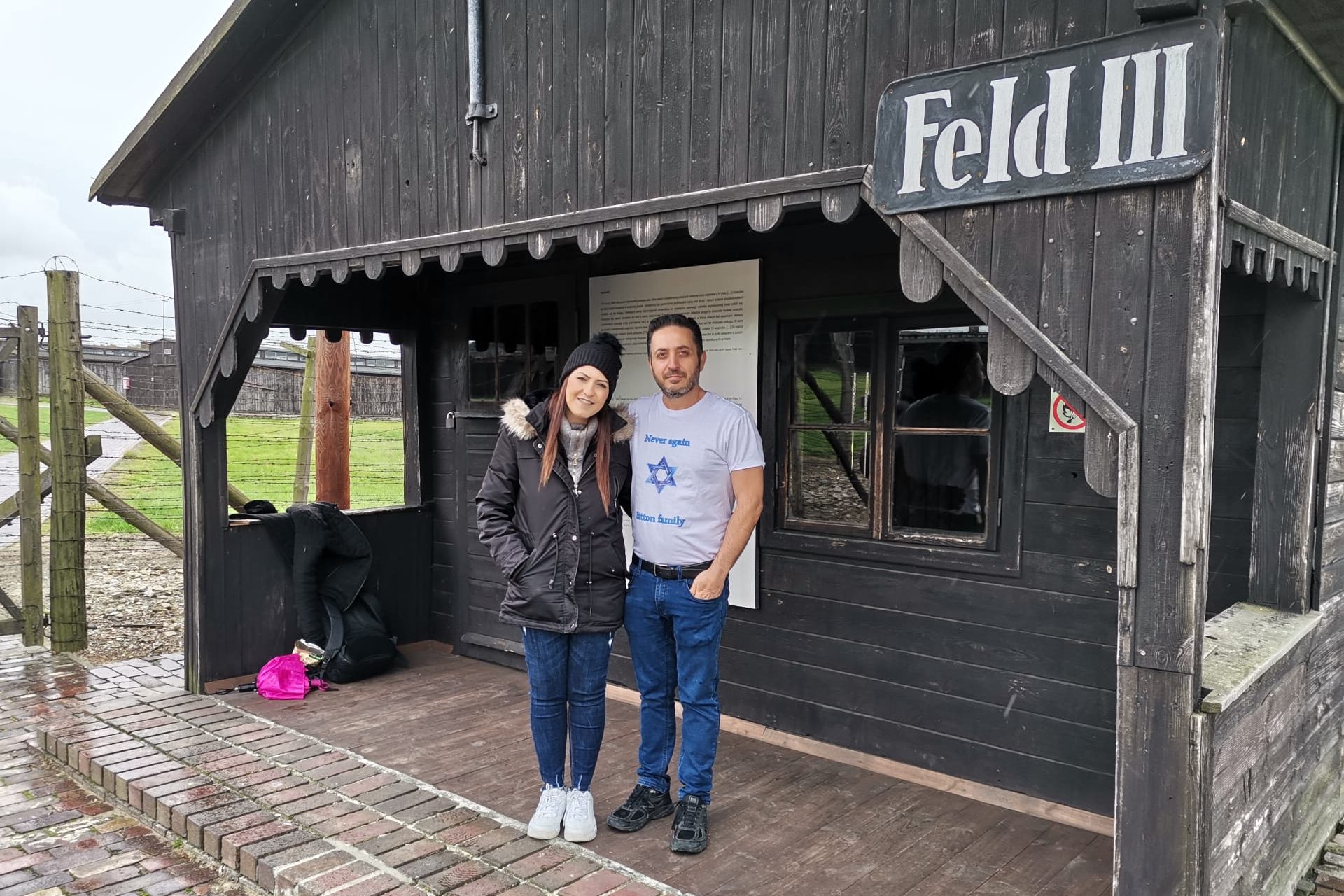 Two visitors standing before the Field 3 Gate House at Majdanek, highlighting the entrance to this significant historical site in Lublin, Poland.